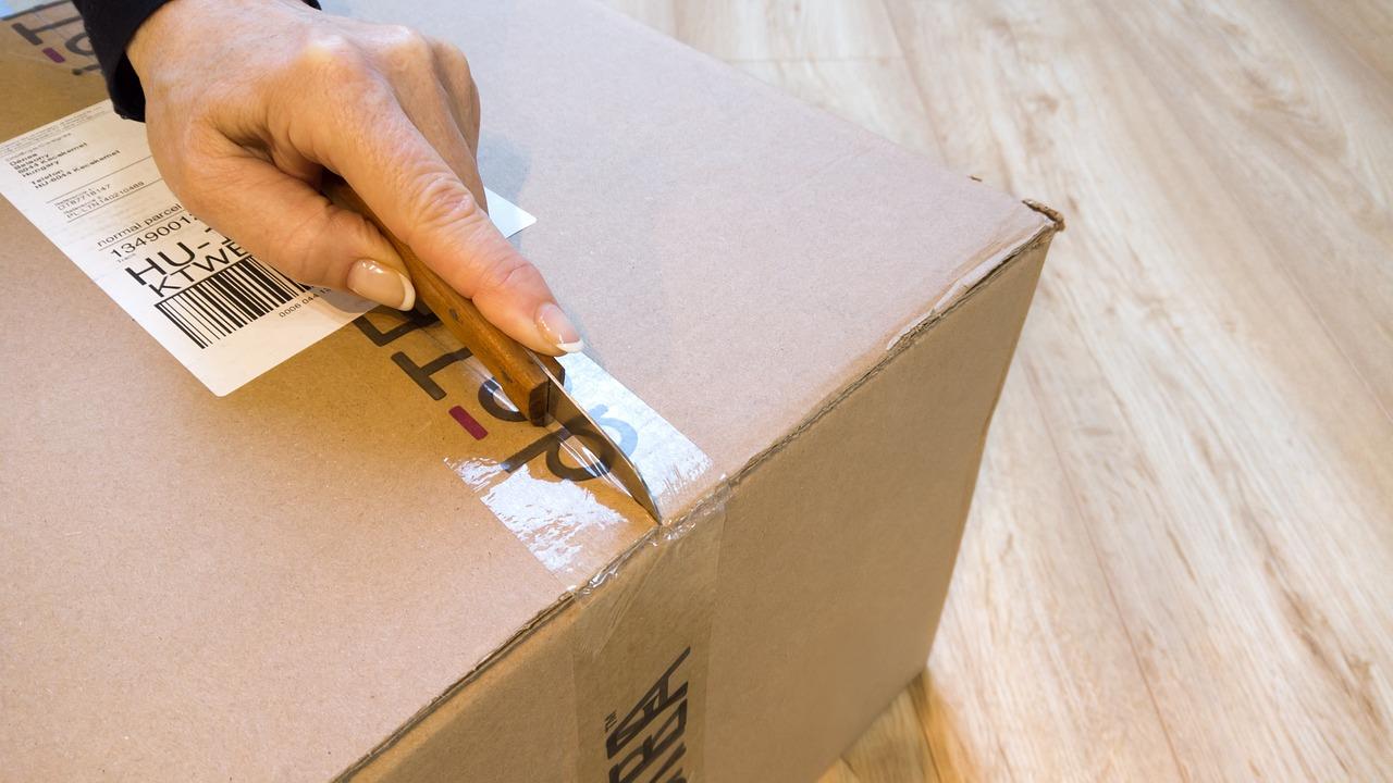 Hand met een tapesnijder om dozen te openen in Amersfoort