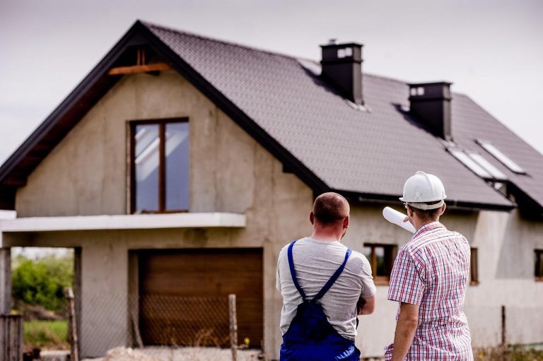 Twee mannen staan ​​en kijken naar een huis in aanbouw. Terwijl de tweede man naar het huis wees, luisterde de eerste man aandachtig in Amersfoort